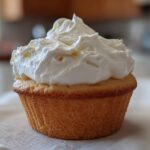 A single vanilla cupcake topped with a generous swirl of fluffy white Cool Whip frosting.