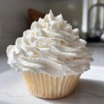 A single vanilla cupcake generously topped with tall swirls of bright white Cool Whip Frosting.