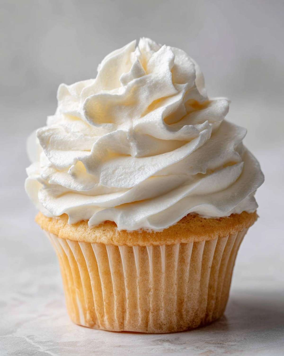 Close-up of a vanilla cupcake topped high with perfectly piped white Cool Whip Frosting.