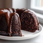 Close-up of a rich Death By Chocolate Bundt Cake with a thick chocolate glaze dripping down the sides.