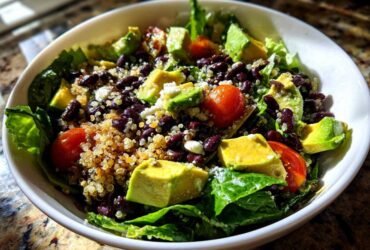 Close-up of a vibrant Fresh Avocado Bowl featuring avocado chunks, black beans, quinoa, cherry tomatoes, and lettuce.