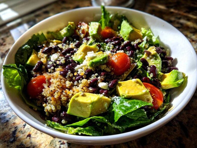 Close-up of a vibrant Fresh Avocado Bowl featuring avocado chunks, black beans, quinoa, cherry tomatoes, and lettuce.