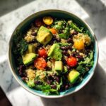 Overhead view of a colorful Fresh Avocado Bowl featuring quinoa, black beans, avocado chunks, and cherry tomatoes.