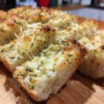 Close-up of freshly baked Garlic Bread with Cheese, showing melted cheese and herbs on sliced bread.