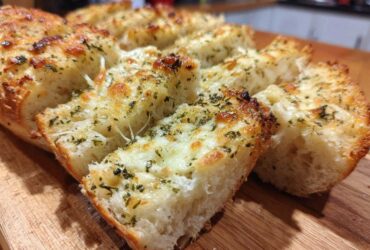 Close-up of freshly baked Garlic Bread with Cheese, showing melted cheese and herbs on sliced bread.