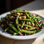 A close-up of Lemon Basil Three Bean Salad featuring green beans, kidney beans, and chickpeas tossed in a dressing.
