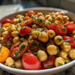 Close-up of a vibrant Mediterranean Diet Chickpea Salad featuring chickpeas, halved cherry tomatoes, and fresh herbs in a white bowl.