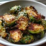 Close-up of crispy Oven Roasted Brussels Sprouts with Parmesan served in a light-colored bowl.