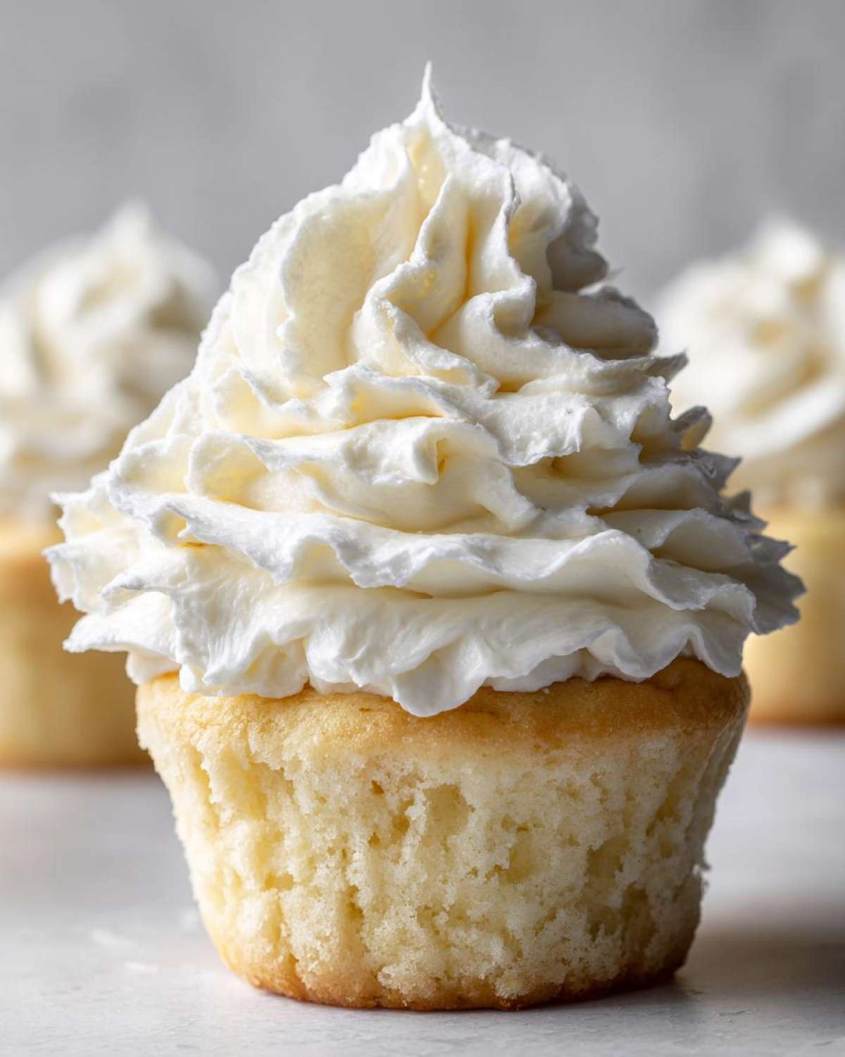 Close-up of a vanilla cupcake topped with a tall swirl of fluffy white Cool Whip Frosting.