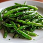Close-up of bright green beans tossed in a savory herb dressing, part of the Greek Bean Salad recipe.