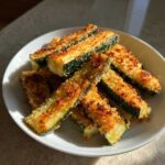 Close-up of crispy Baked Parmesan Zucchini sticks piled in a white bowl, perfectly golden brown.