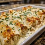 Close-up of baked Creamy White Chicken Enchiladas covered in melted, browned cheese and parsley.