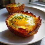 Close-up of a crispy Hash Brown Breakfast Cup topped with a perfectly cooked egg and fresh chives.