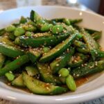 A close-up of a bright green Edamame and Cucumber Salad tossed in a savory dressing and topped with sesame seeds.