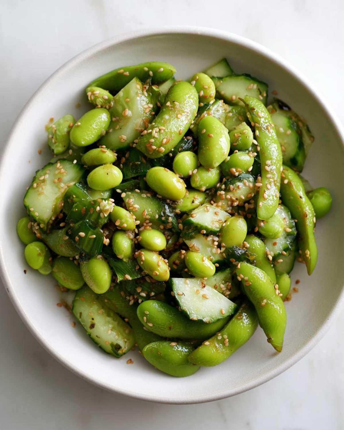 Close-up of a vibrant Edamame and Cucumber Salad topped generously with toasted sesame seeds.