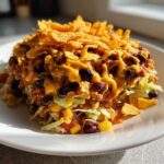 A tall serving of Frito Cowboy Cabbage Salad topped with melted cheese sauce and crunchy Fritos corn chips.