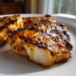 A close-up of perfectly cooked Grilled Honey Mustard Chicken Breasts, showing a juicy white interior and caramelized, seasoned exterior.