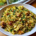 Close-up of a white bowl filled with Lemon Chicken Orzo Stir Fry, garnished with fresh herbs.