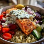 Close-up of a vibrant Mediterranean Salmon Bowl featuring seasoned salmon topped with tzatziki sauce over quinoa.