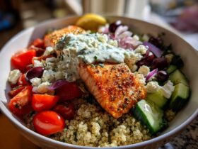 Close-up of a vibrant Mediterranean Salmon Bowl featuring seasoned salmon topped with tzatziki sauce over quinoa.