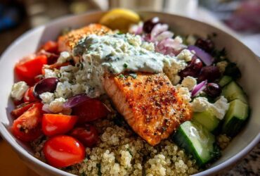 Close-up of a vibrant Mediterranean Salmon Bowl featuring seasoned salmon topped with tzatziki sauce over quinoa.