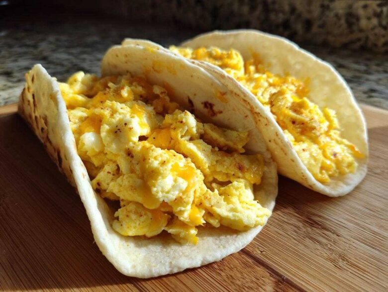 Two soft flour tortillas filled with fluffy scrambled eggs and melted cheese, perfect Potato Egg Cheese Breakfast Tacos.
