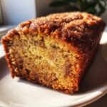 A close-up, sunlit shot of a moist slice of Snickerdoodle Banana Bread showing the cinnamon swirl texture.
