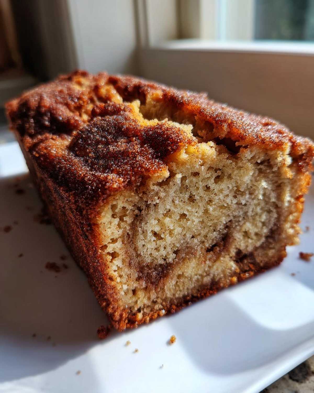 Close-up of a slice of Snickerdoodle Banana Bread showing a moist crumb and cinnamon swirl topping.